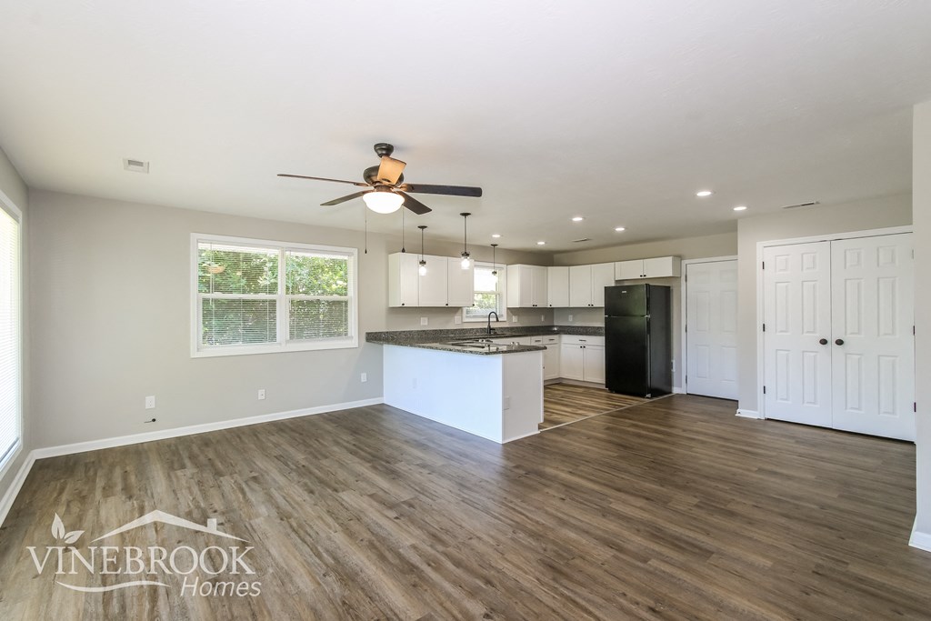 A spacious kitchen with a ceiling fan and wooden flooring.