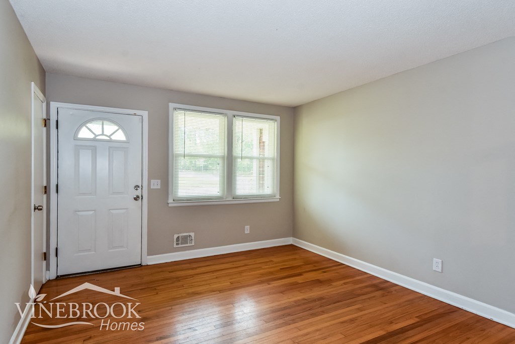 the living room of a house with a wooden floor and a white door