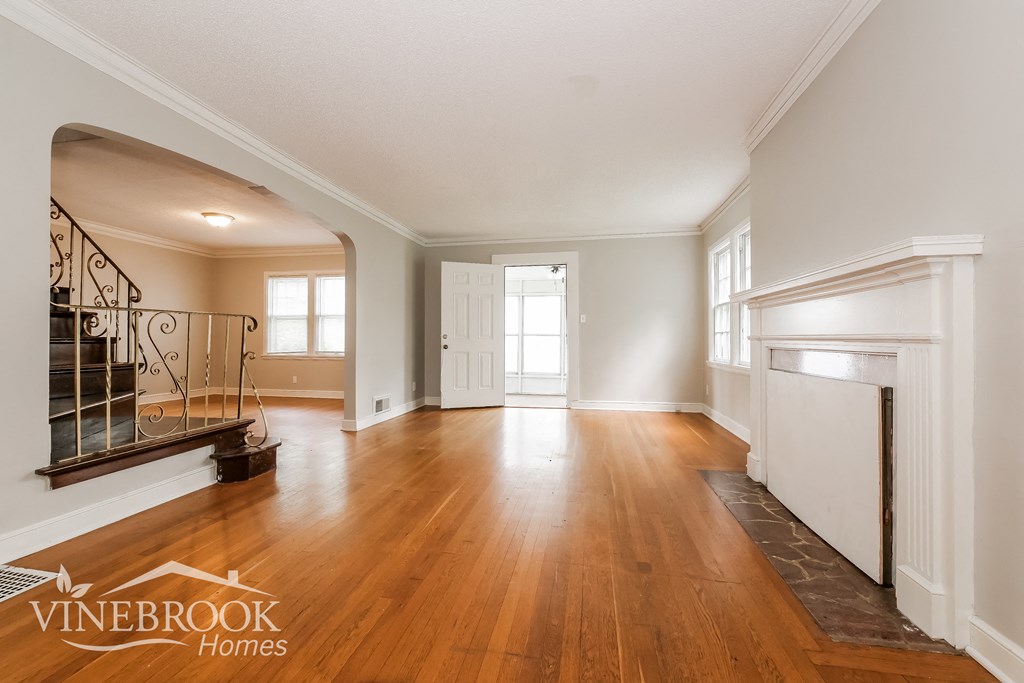 an empty living room with a fireplace and hardwood floors
