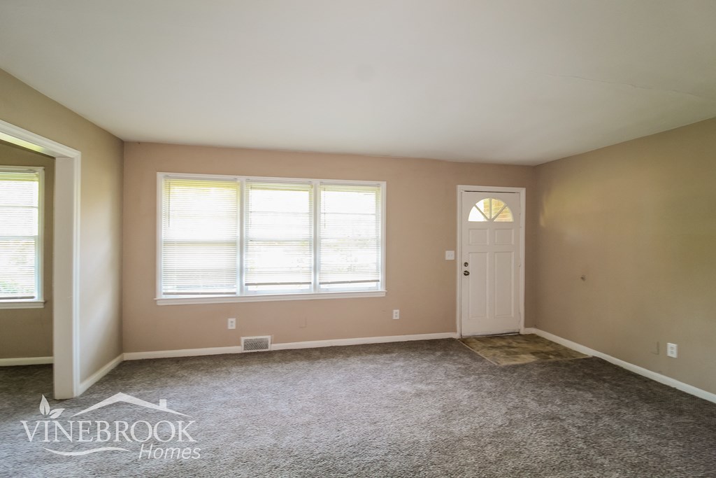 a room with carpet and a white door and window