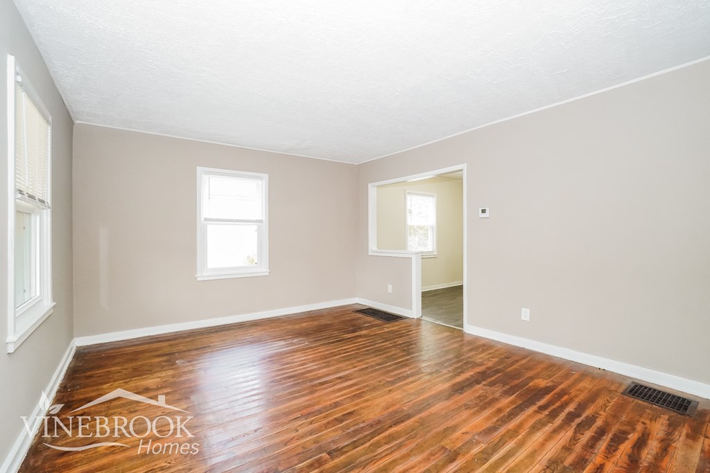 the living room and dining room with wood floors and white walls
