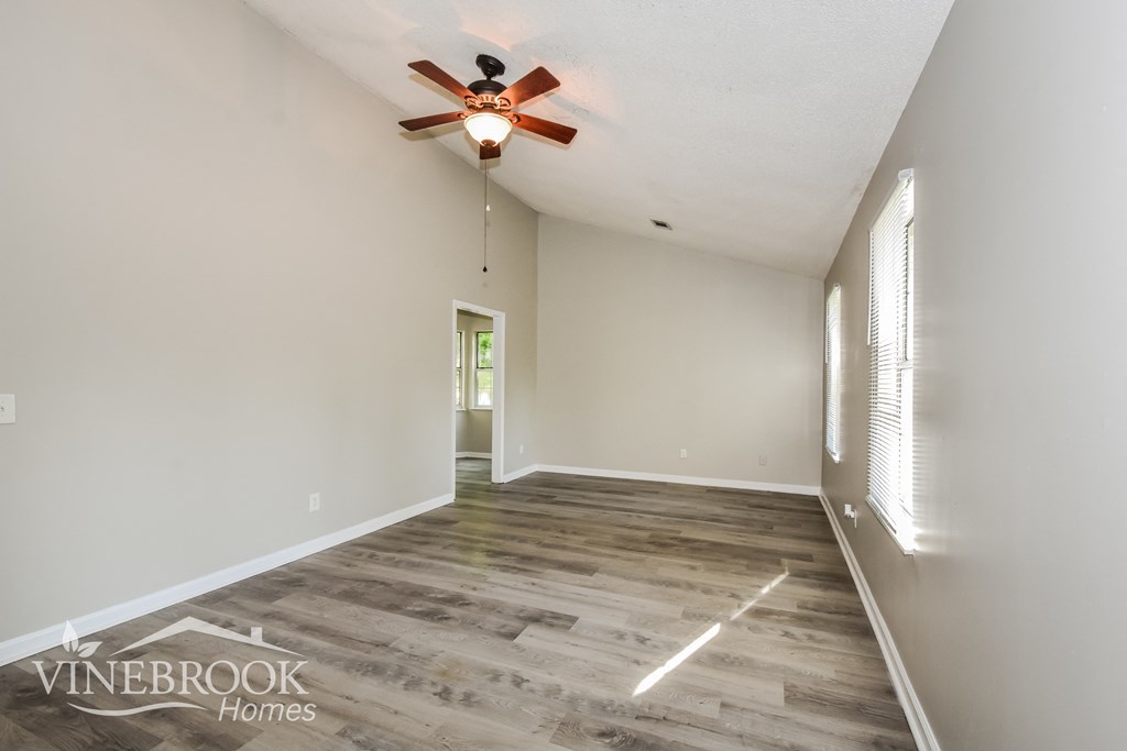 a spacious living room with white walls and a ceiling fan