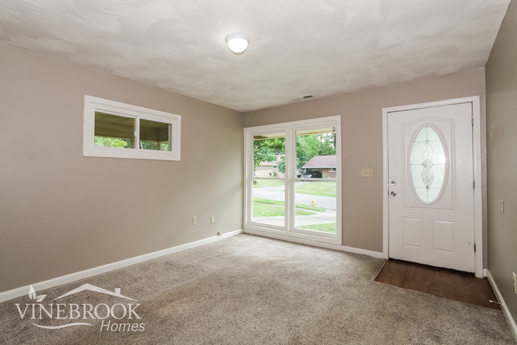 a living room with a white door and a carpeted floor