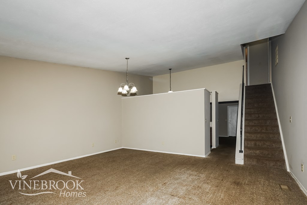 a living room with a staircase and a white wall
