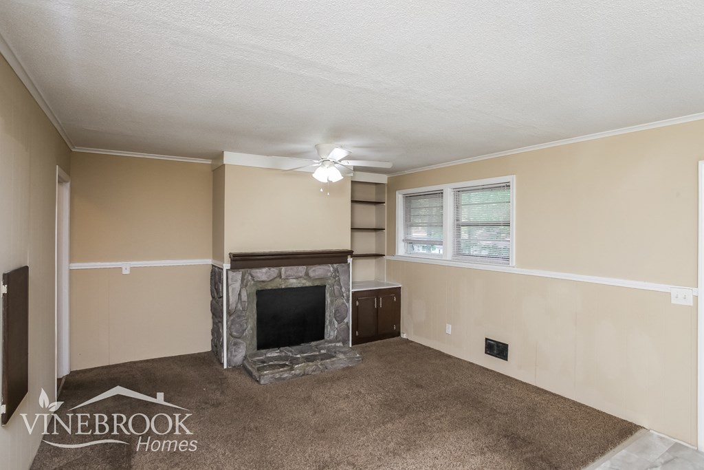 an empty living room with a fireplace and a window