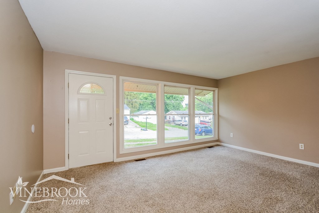 the living room of a home with large windows and a white door