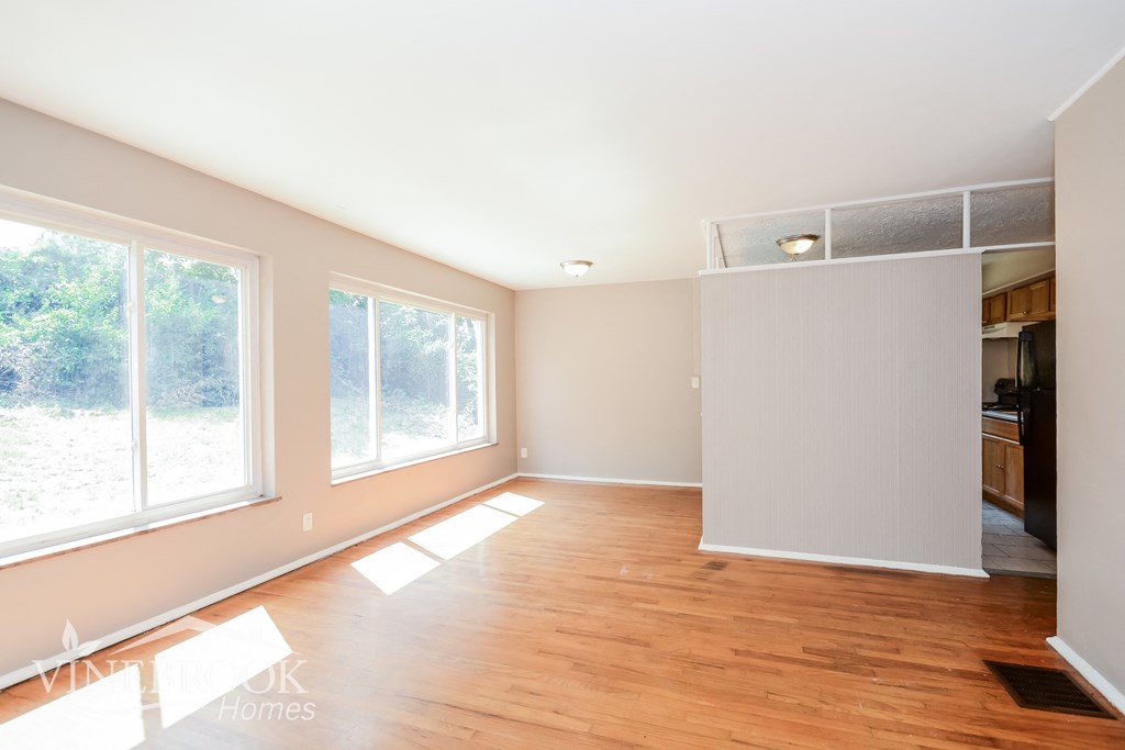 an empty living room with wood floors and large windows
