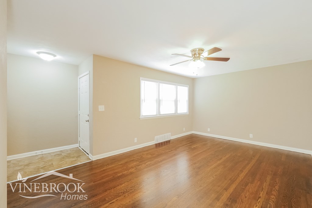 the living room of a home with wood floors and a ceiling fan
