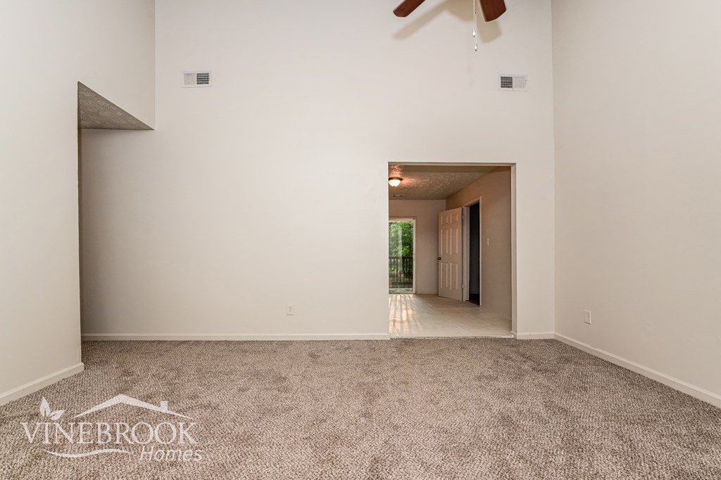 a living room with carpet and a ceiling fan