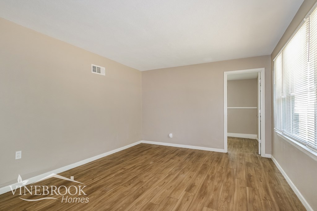 the living room of an apartment with wood floors and white walls