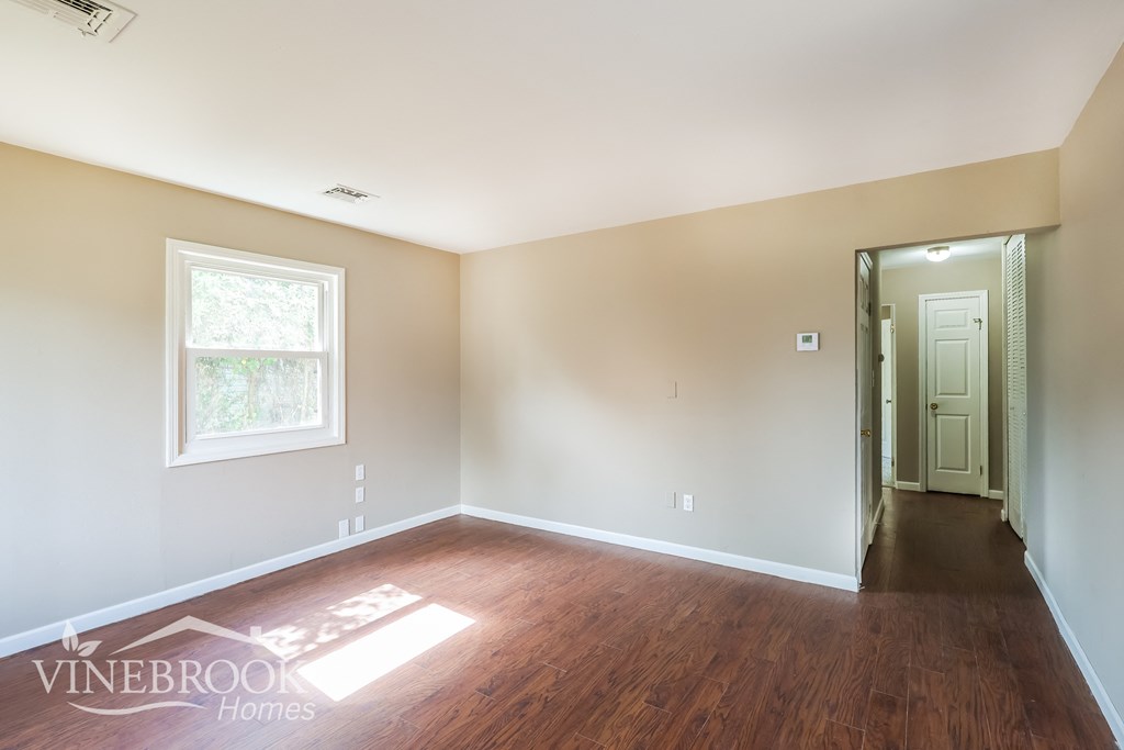 an empty living room with wood floors and a white door