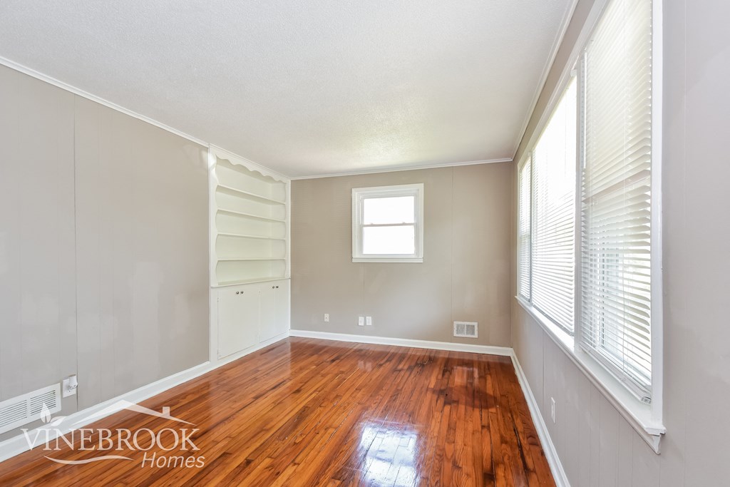 a bedroom with a wood floor and white shelves and a window