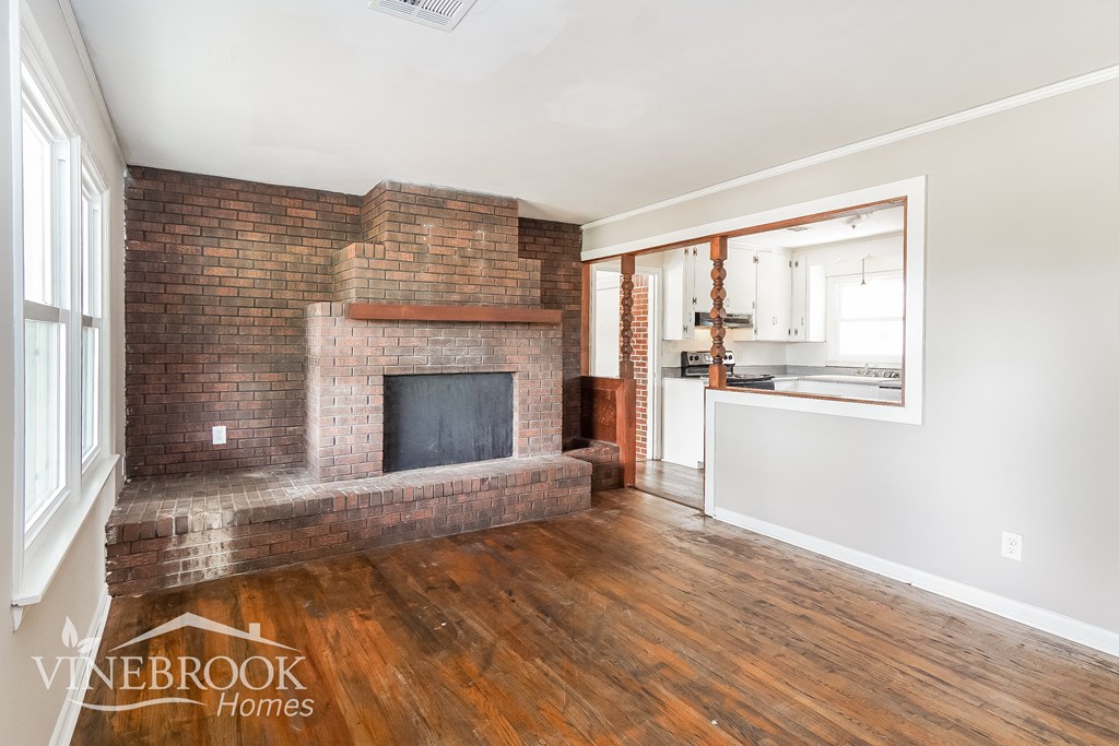 a living room with a brick fireplace and wooden floors