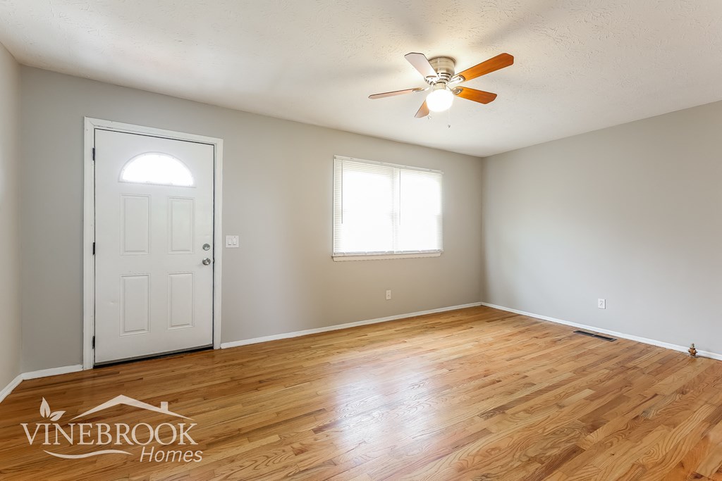 the living room of a home with a wood floor and a ceiling fan