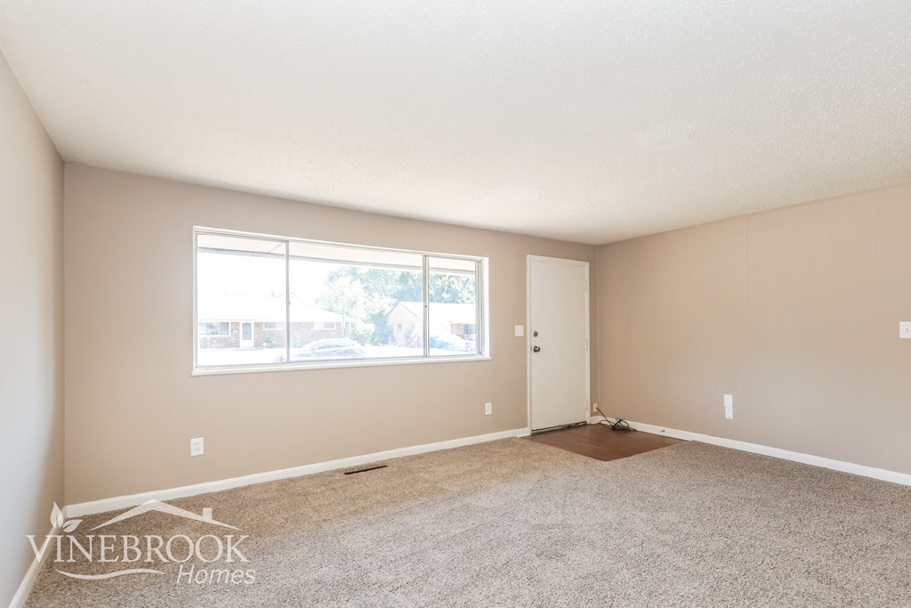 a spacious living room with carpet and a large window