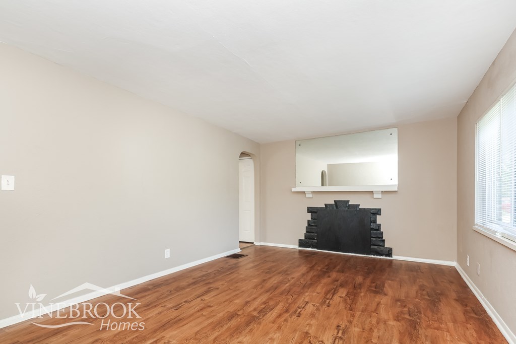 an empty living room with wood flooring and a fireplace