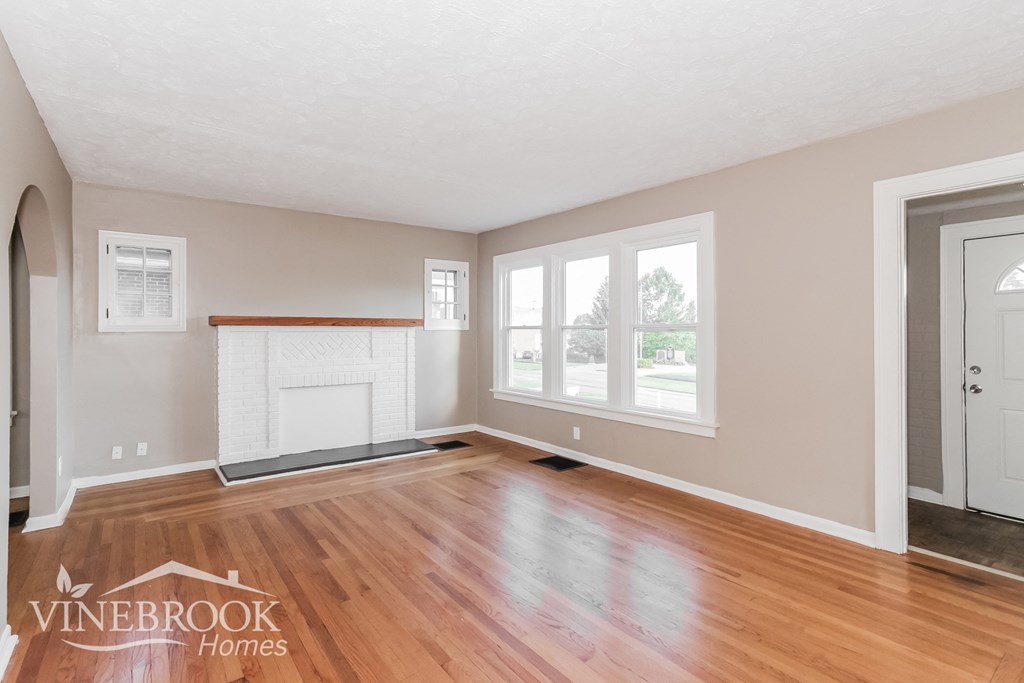 an empty living room with wood floors and a fireplace