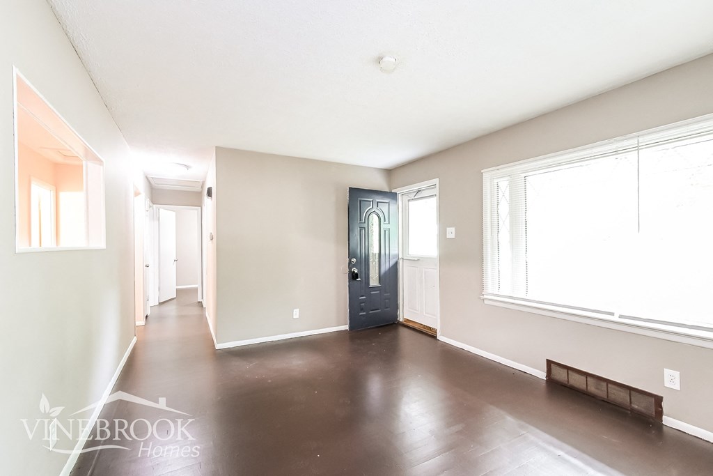 a large empty living room with white walls and a blue door