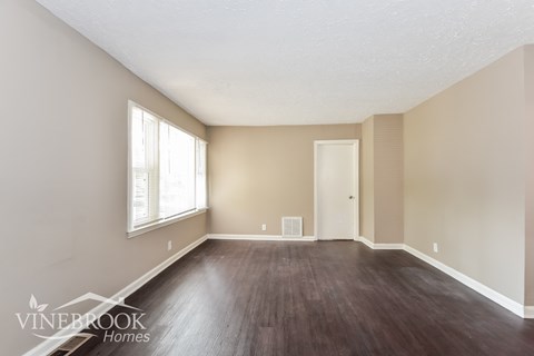 the living room of an apartment with wood floors and beige walls