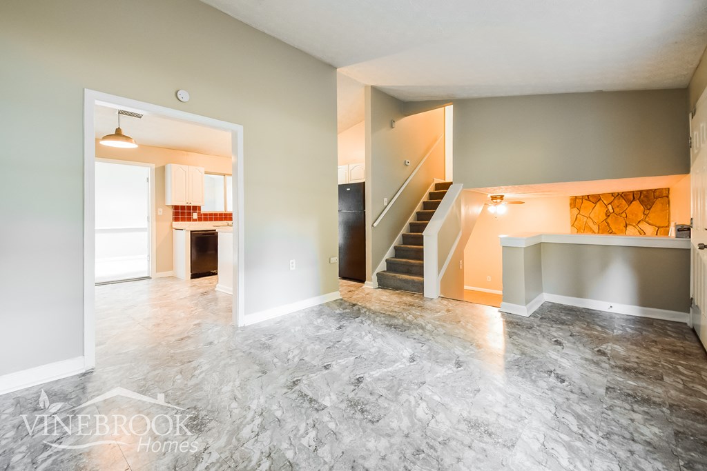a renovated living room with a staircase and a marble floor