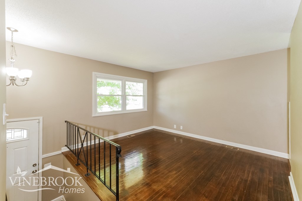 a living room with a hardwood floor and a staircase