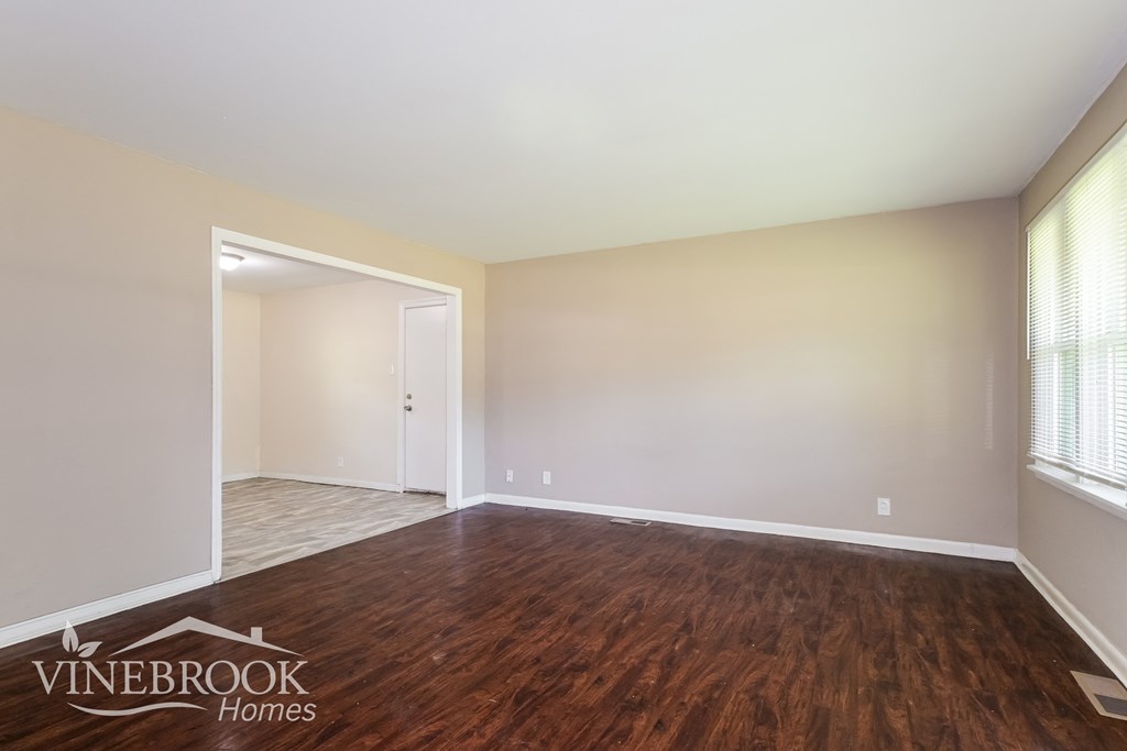 the living room of an apartment with wood flooring and white walls