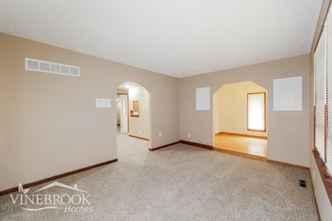 the living room and dining room of a home with white carpet and white walls