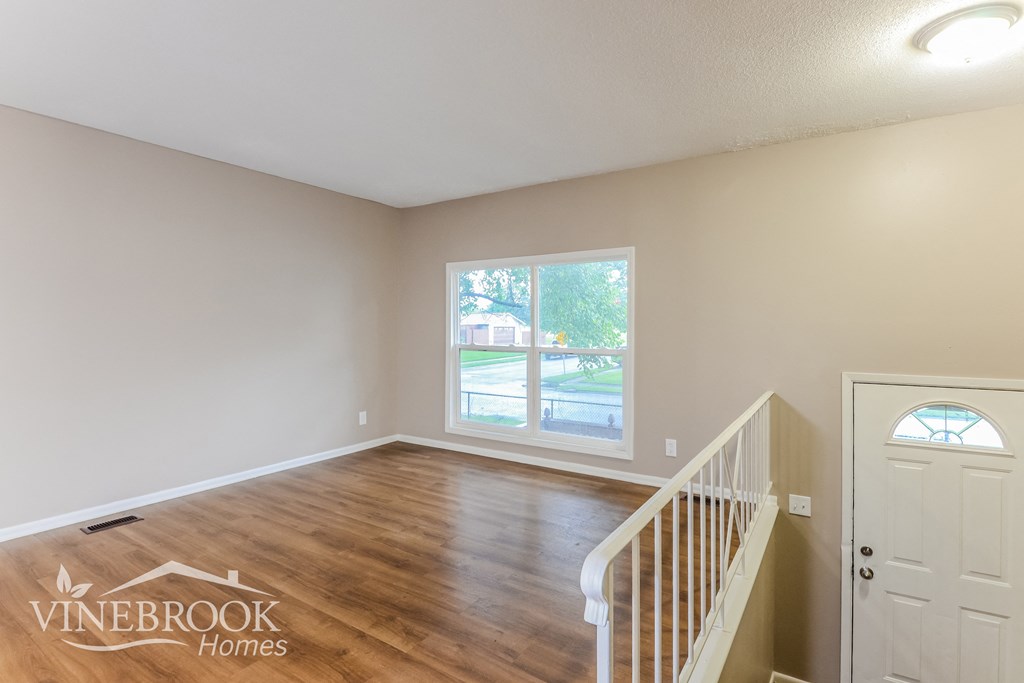 the living room of a house with a staircase and a window