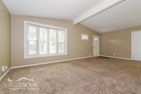 the living room of a home with carpet and a large window