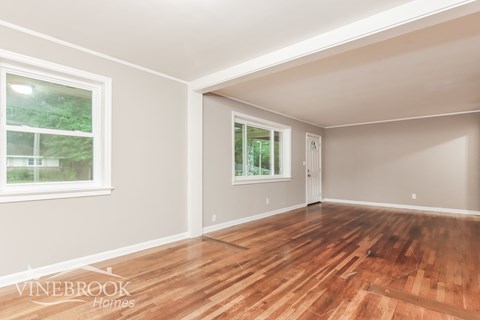 A room with wooden floors and a window showing greenery outside.