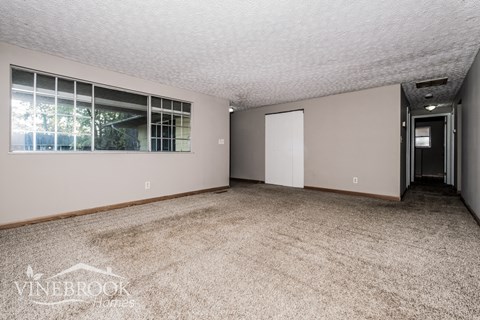 the living room of a home with carpet and a door to a hallway