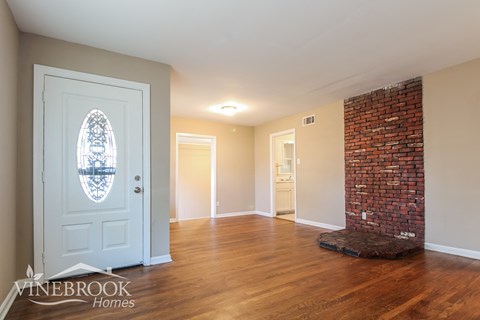 A room with a white door and a brick wall.