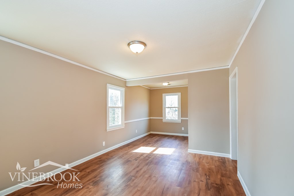 A room with wooden floors and two windows.