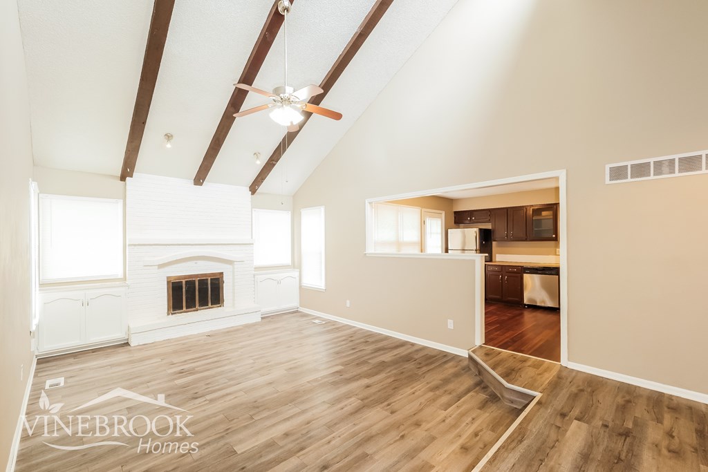 A spacious room with wood flooring and a fireplace.