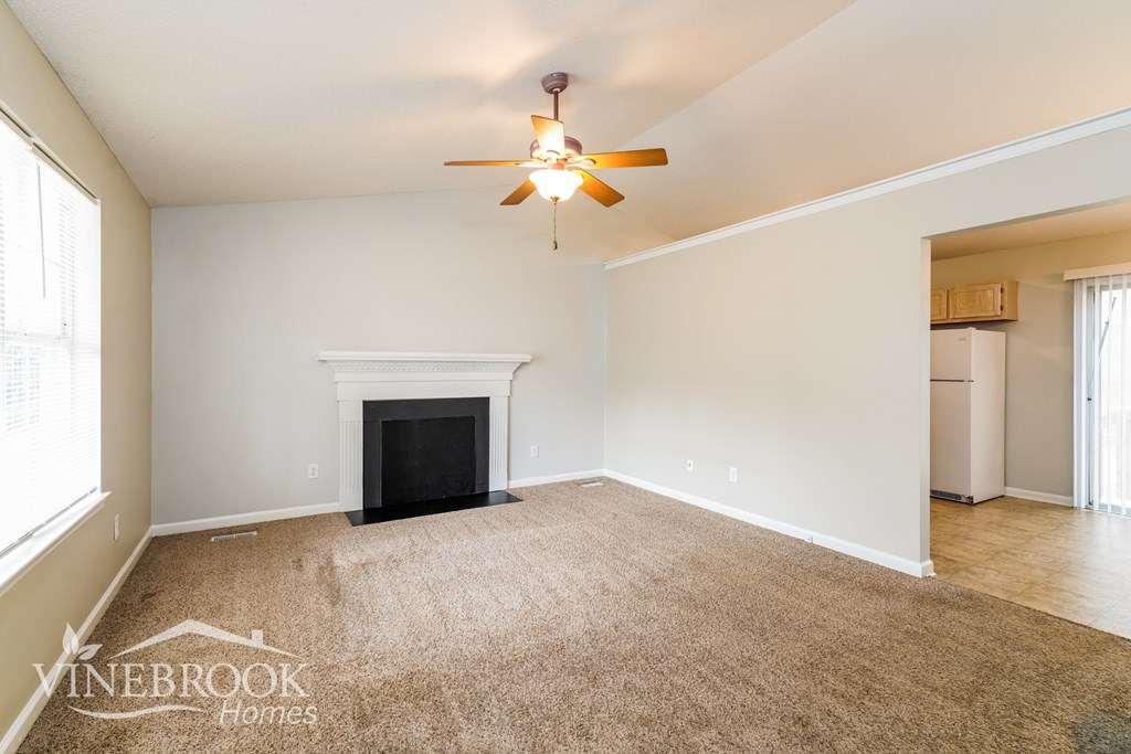 A living room with a fireplace and a ceiling fan.