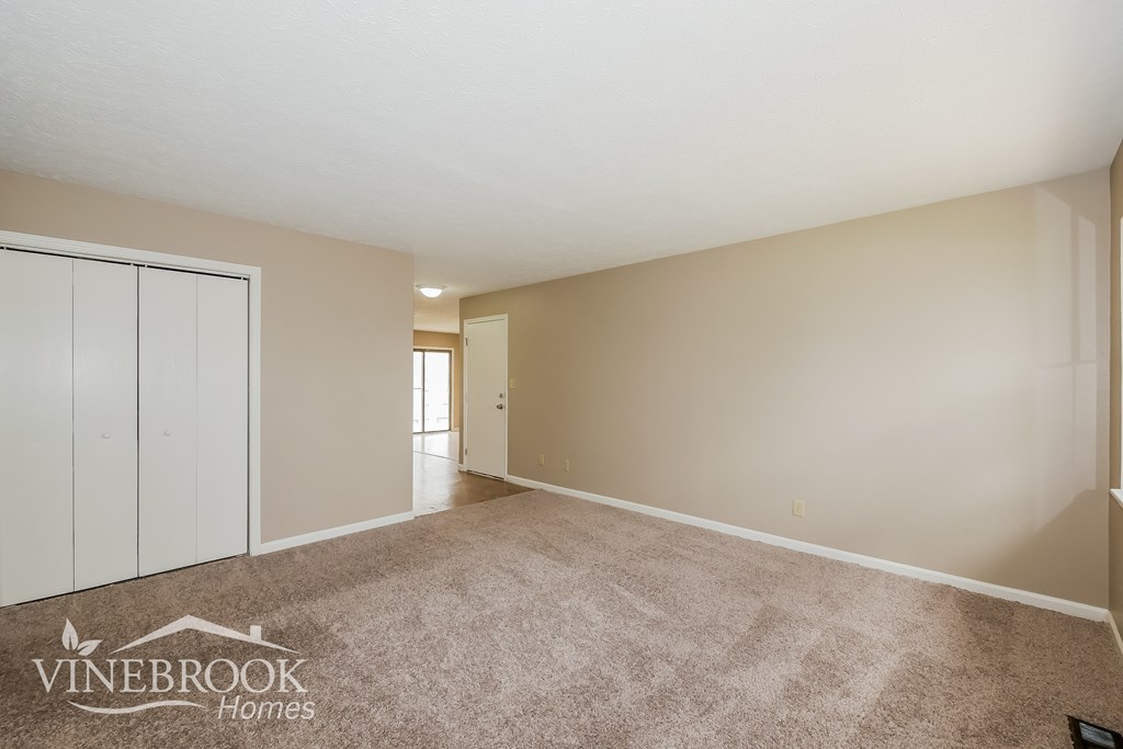 A room with a carpeted floor and a wall with a Vinebrook Homes logo.