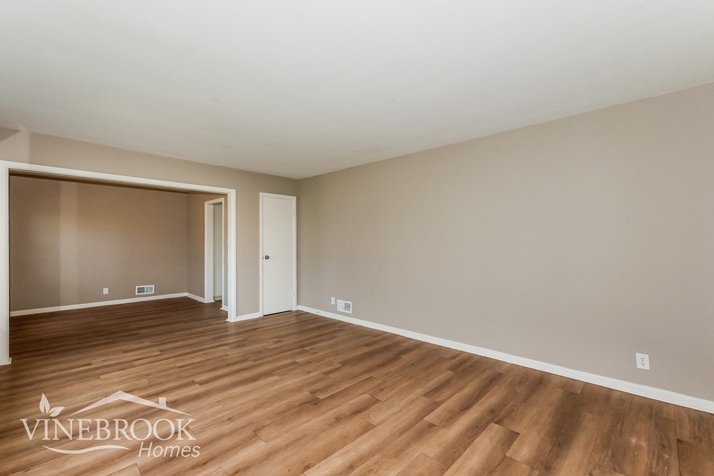 A room with wood flooring and a logo for Vinebrook Homes.