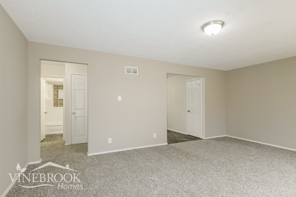 A room with a carpeted floor and two doors.