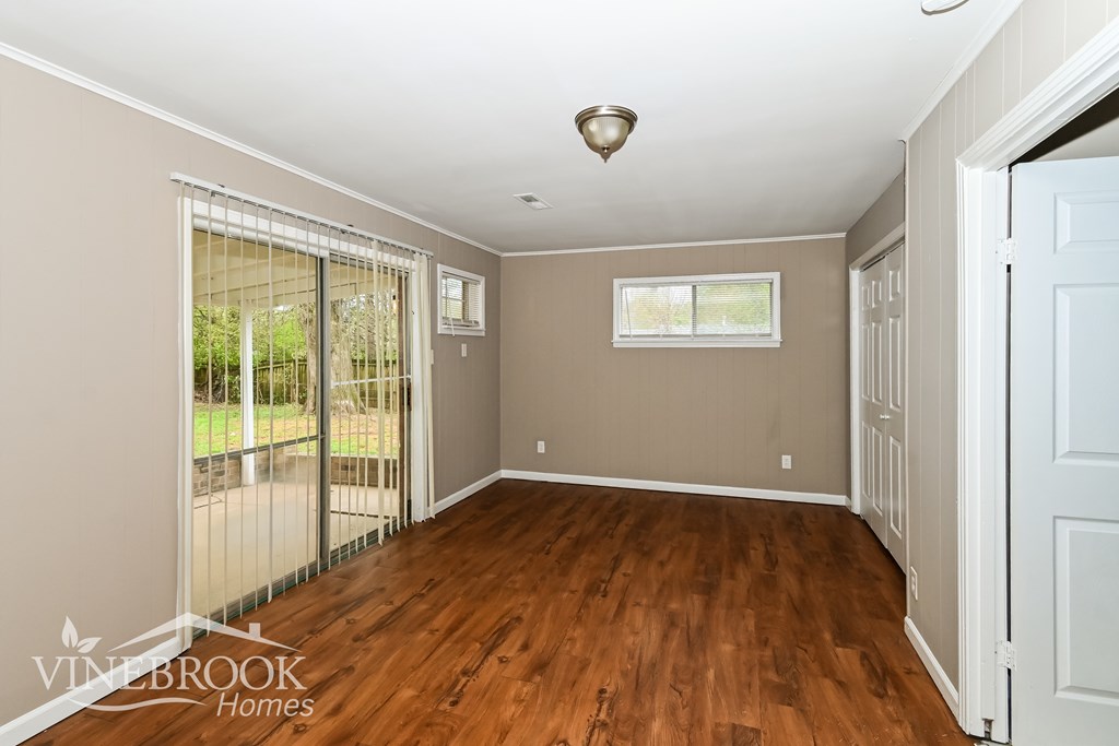 A room with wood flooring and a sliding glass door leading to a backyard.