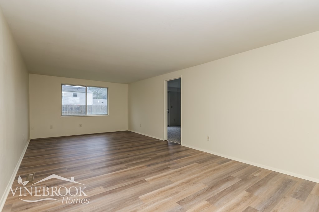 A room with wooden flooring and a window with a view of a building outside.