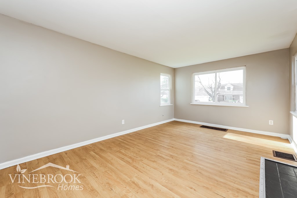 A room with wooden flooring and a window showing a tree outside.