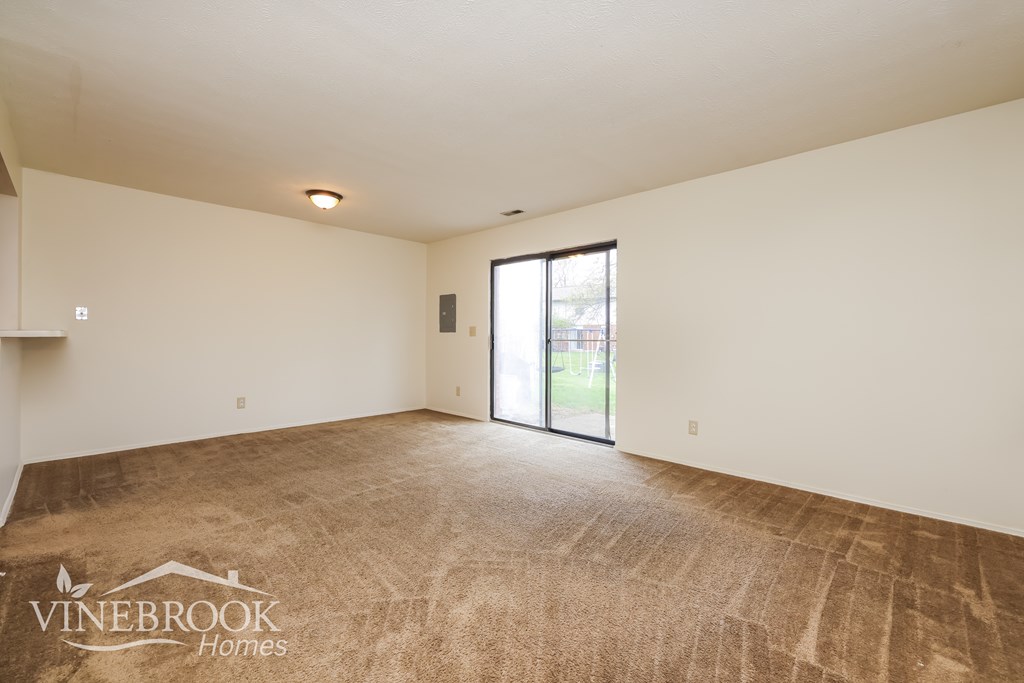 A room with a carpeted floor and a sliding glass door.
