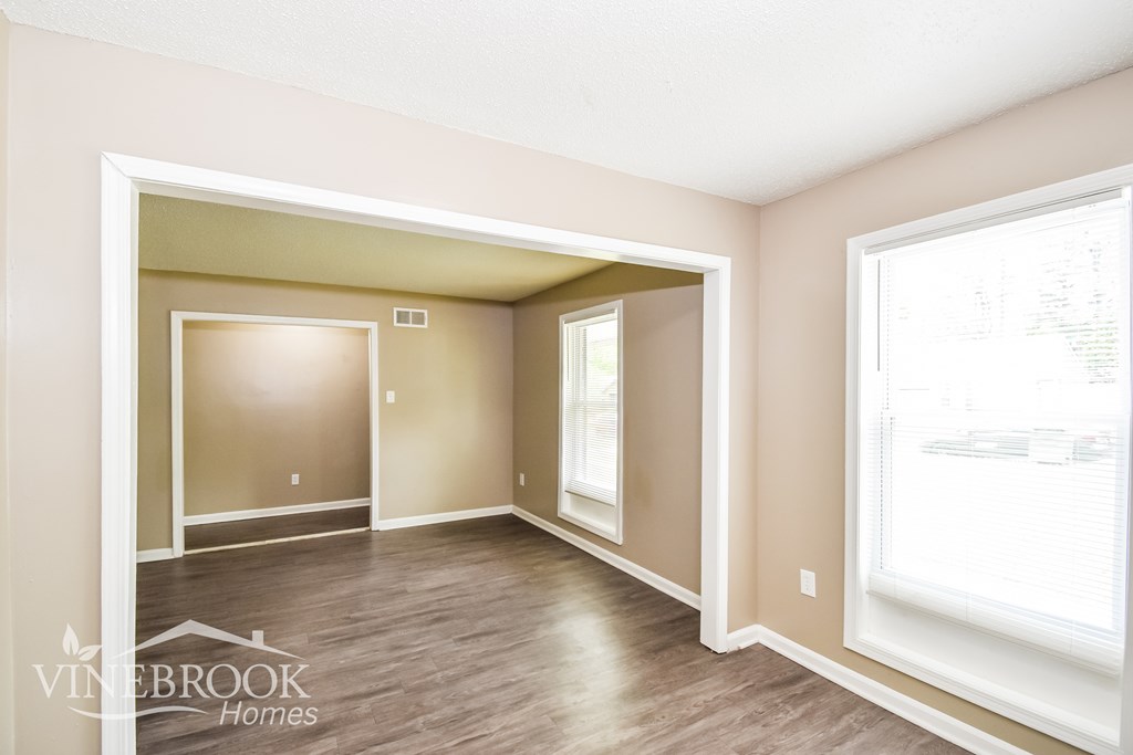 A room with a window and a doorway leading to another room.