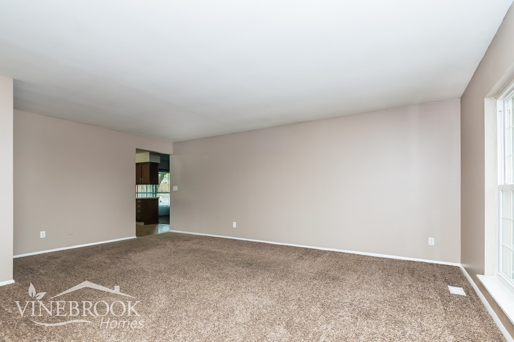 A room with a carpeted floor and a doorway leading to another room.