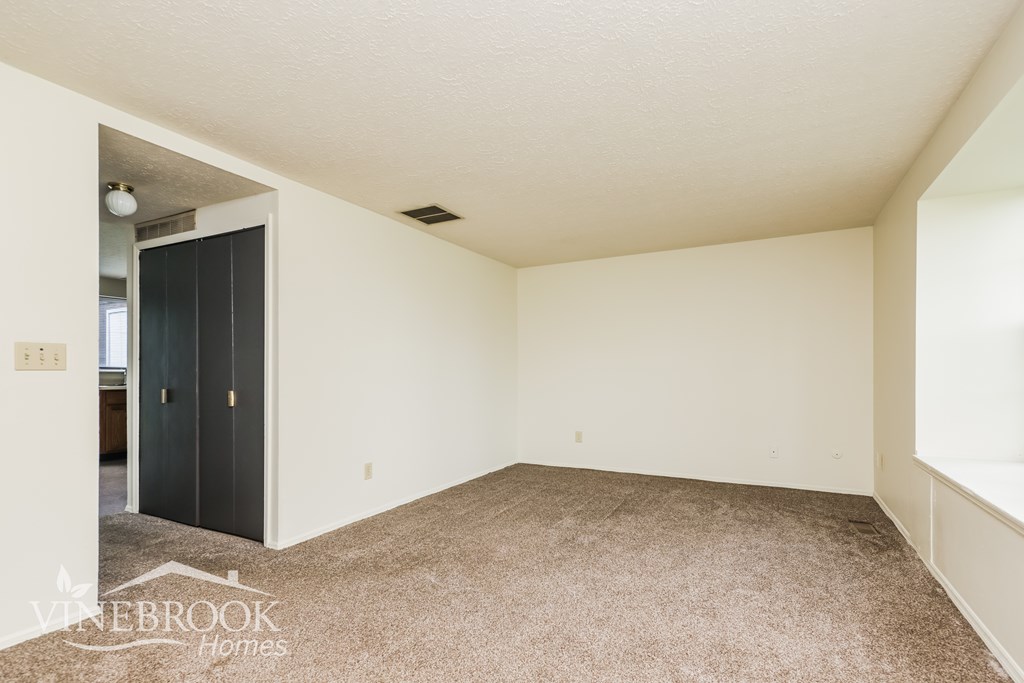 A room with a carpeted floor and a door leading to another room.
