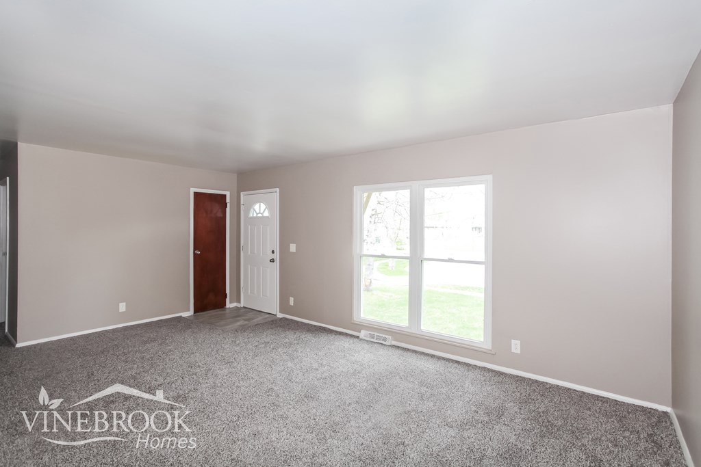A room with a carpeted floor and a door leading to a balcony.