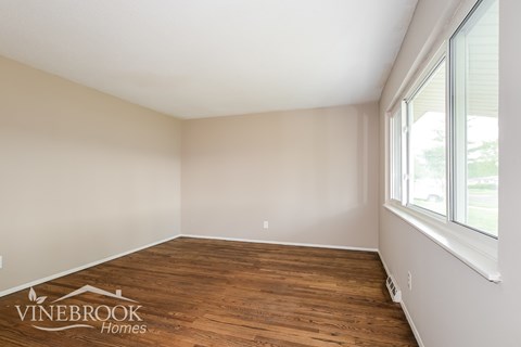 A room with wooden flooring and a window on the right side.
