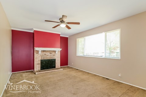 A room with a fireplace and a ceiling fan.