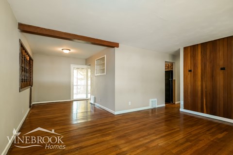 A room with wooden floors and a white wall with a window.