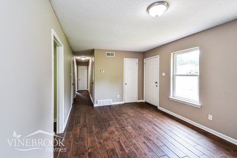 A long hallway with wood floors and white walls.